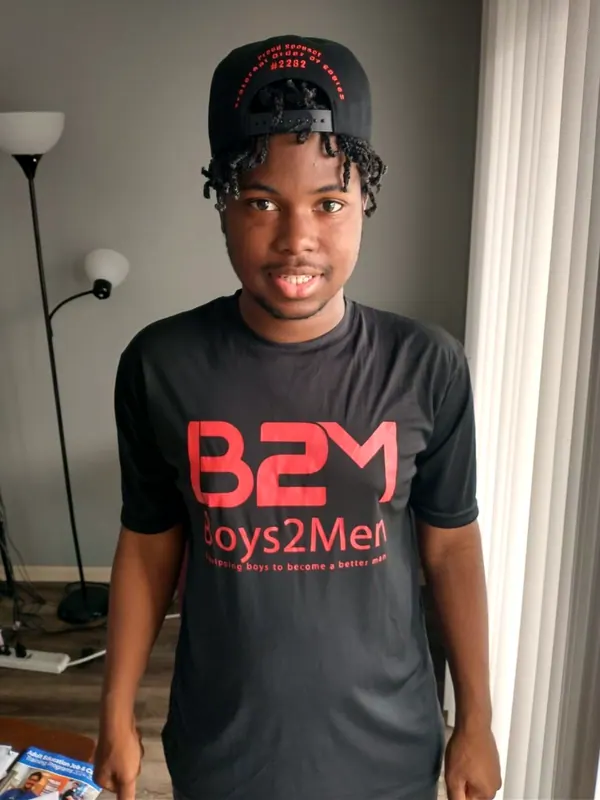 A smiling boy in a Boys2Men shirt.