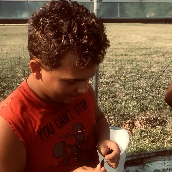 A boy working on a project outside a greenhouse.