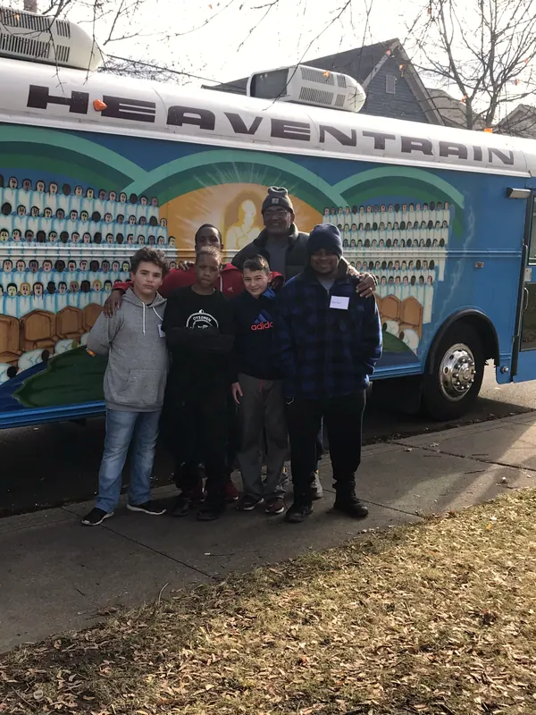 Boys and mentors in front of a painted bus.