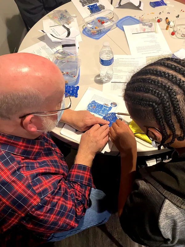 A mentor and a boy working on a project together.