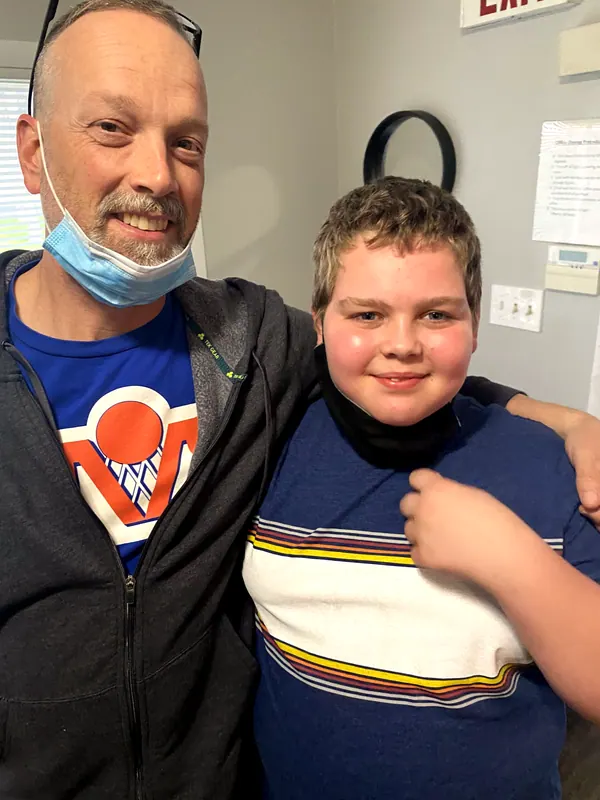 A mentor with his arm around a smiling boy.