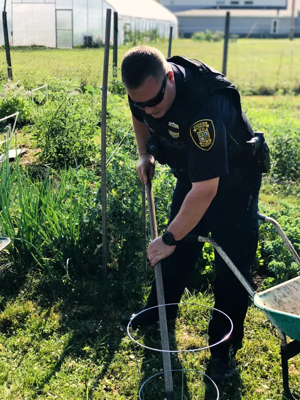 A police officer helping in the garden.