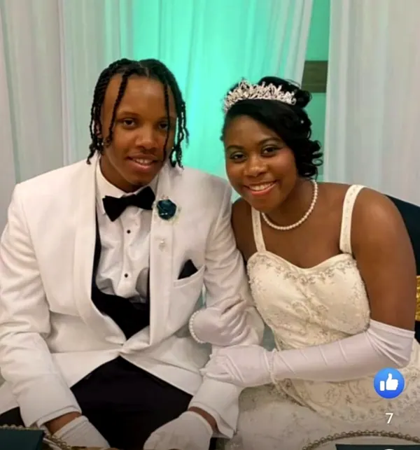 A young man in a white tuxedo beside his date in a white gown.