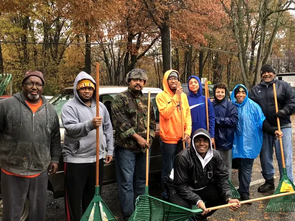 A crew of boys and men with rakes after a service day.