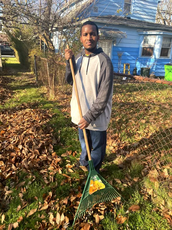A teenager raking a yard.