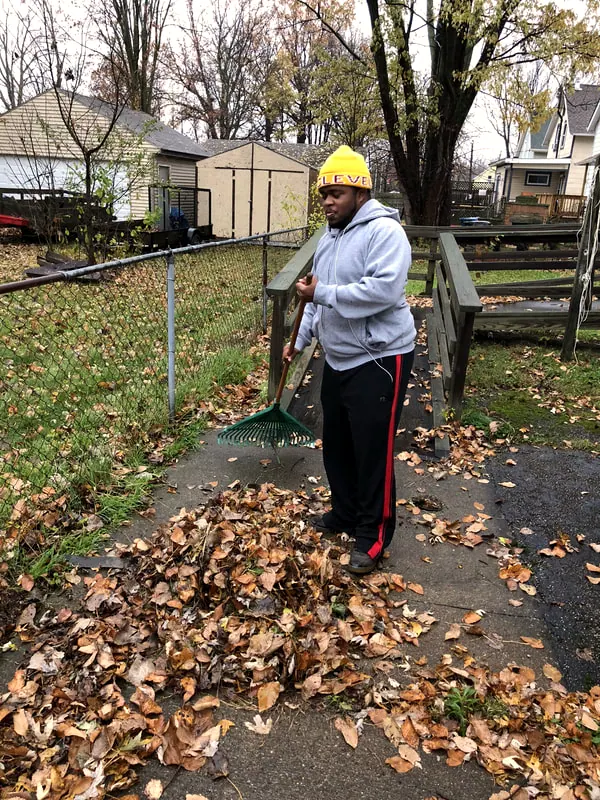 A volunteer clearing leaves from a yard.