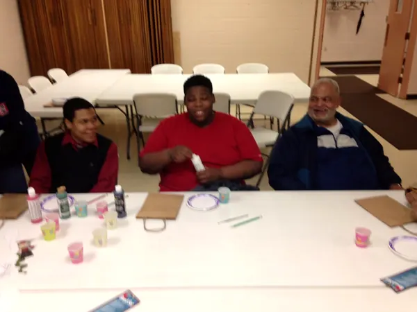 A Boys2Men mentor smiling with boys at a table.